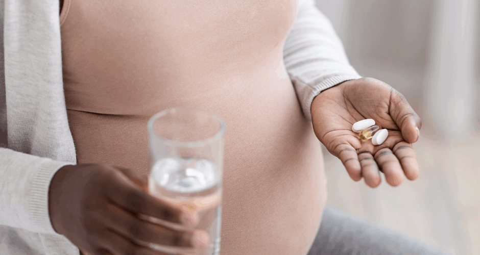 Pregnant mother holding a glass of water and medication