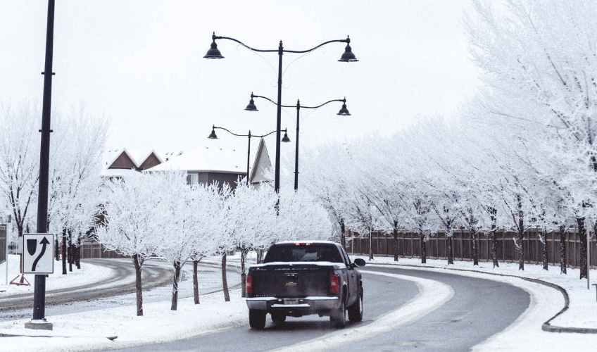 Chevy truck driving on icy roads as surrounding trees are covered with snow