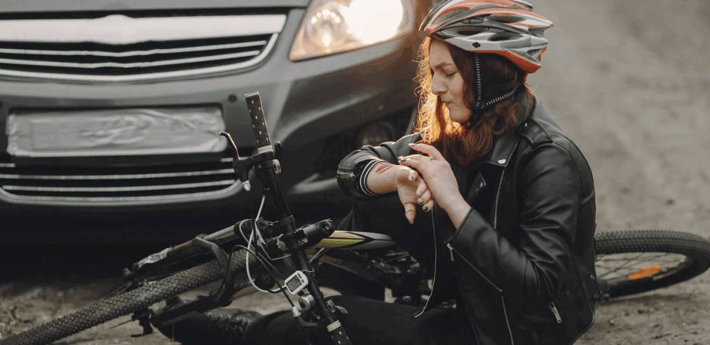 Woman in bicycle helmet with bike on road infront of a car